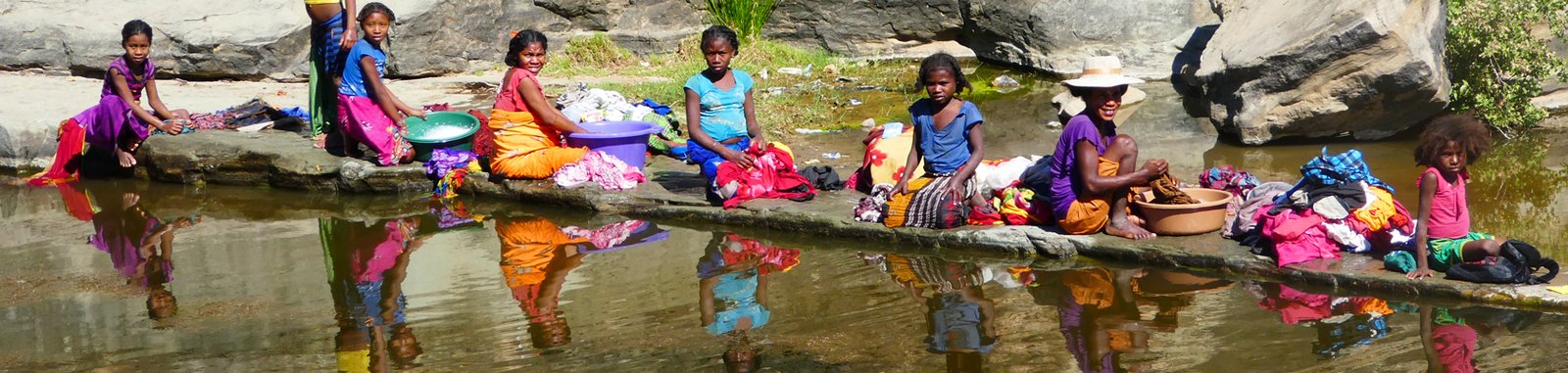 Junge Mädchen waschen am Fluß die Wäsche anderer